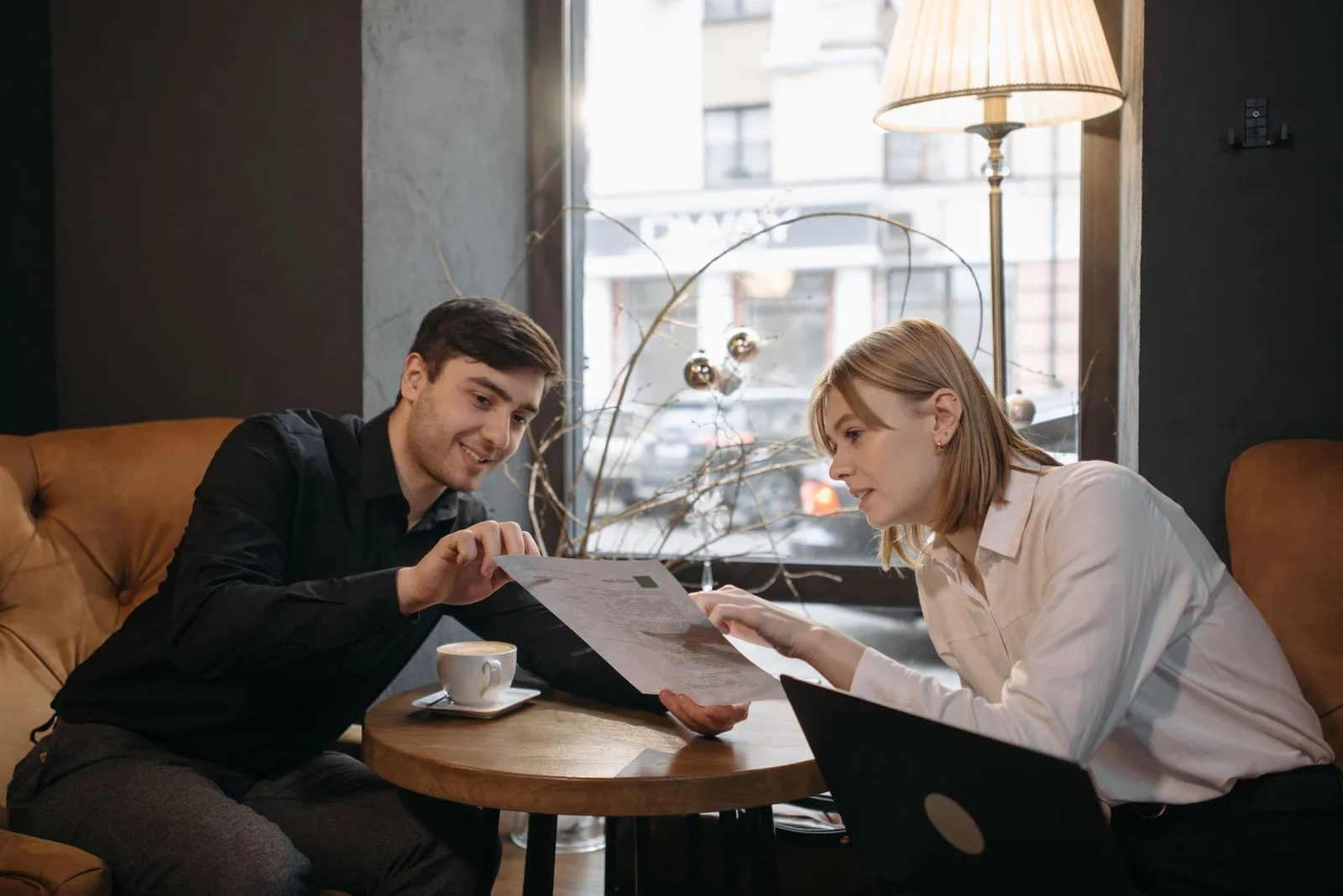 Two people smiling and talking over a document at a small round table